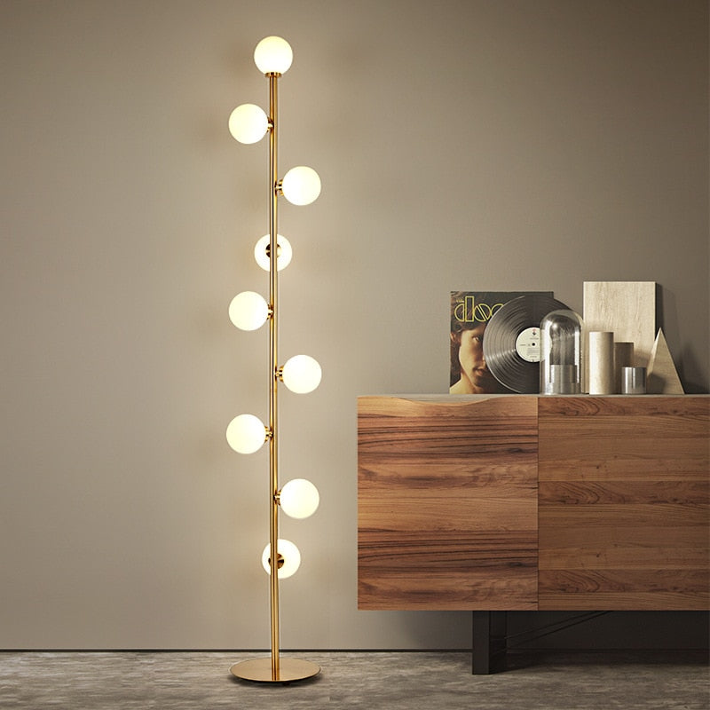 Lampadaire nordique minimaliste Magic Beans avec 9 boules en verre et structure dorée, parfait pour un éclairage élégant et contemporain dans les intérieurs modernes.

